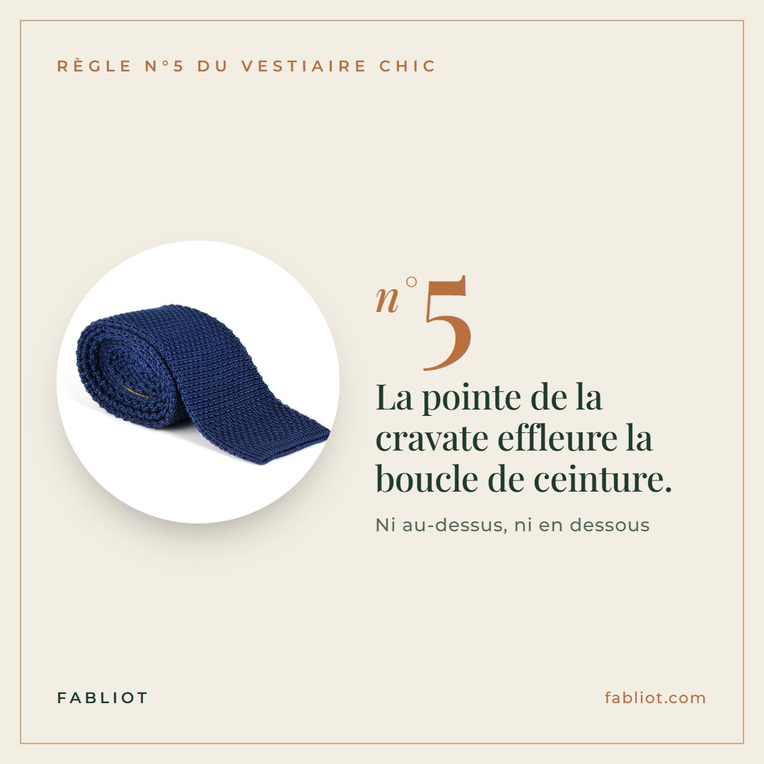 La pointe de la cravate effleure la boucle de ceinture.